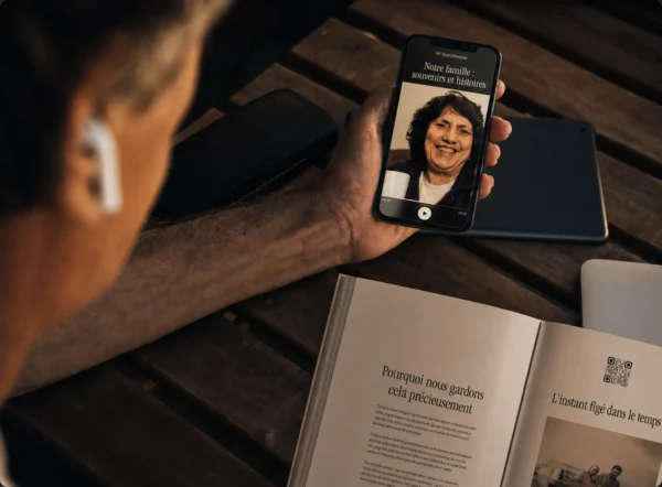 Un téléphone lit un enregistrement accessible par le code QR d’un livre StoryKeeper ouvert.