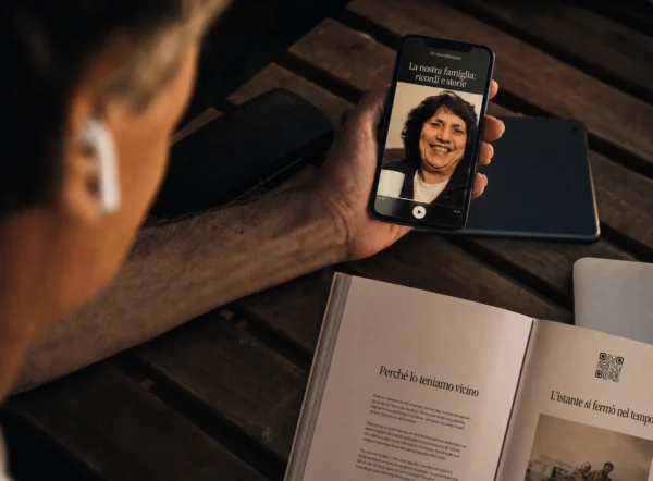 Uno smartphone riproduce una registrazione collegata tramite il codice QR di un libro StoryKeeper aperto.